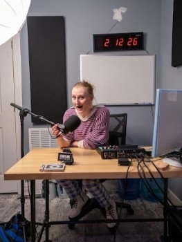 Chrysalis sitting at a recording desk talking into a microphone