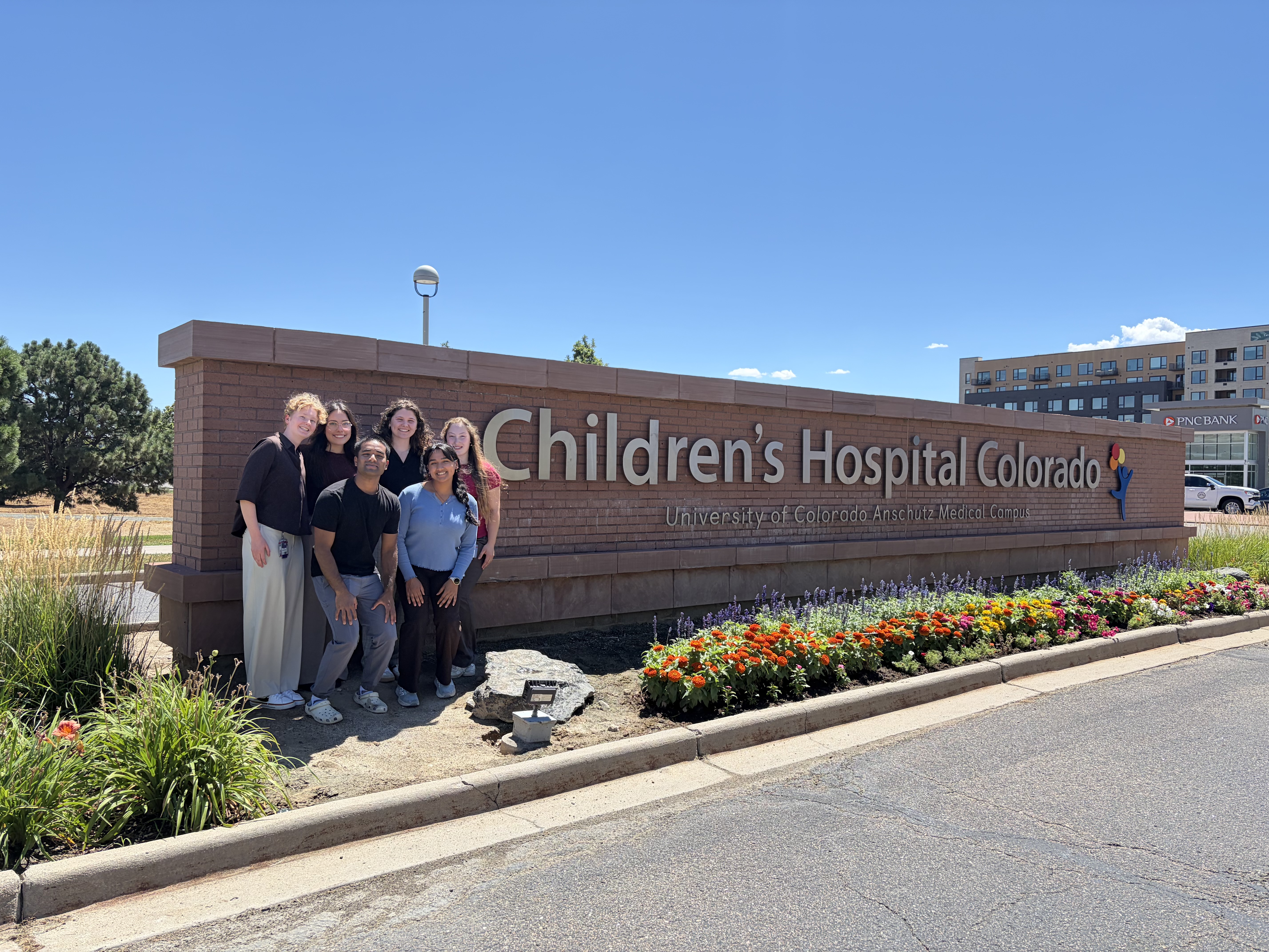 Interns stand in front of the sign for Children's Hospital Colorado.
