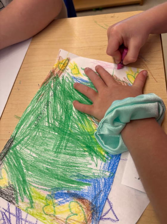 child's hand coloring with a crayon
