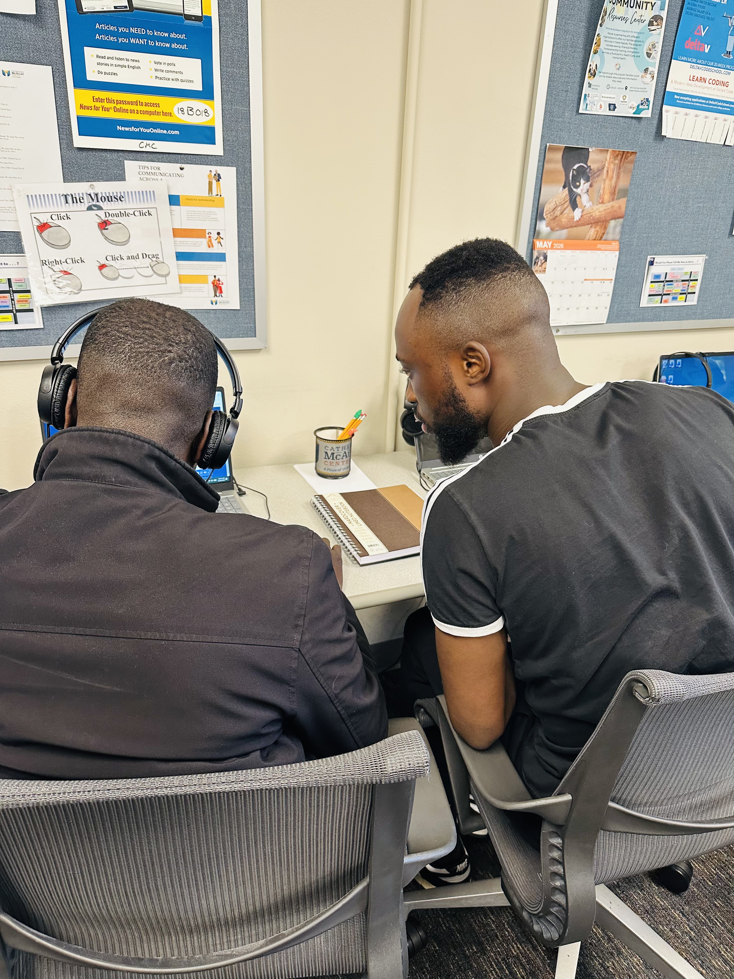 Two men look at a computer.