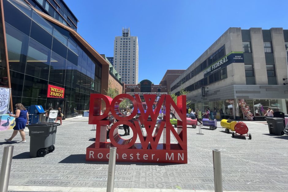 City landscape with a red sign with three rows of text that say DOWN, TOWN, and Rochester MN